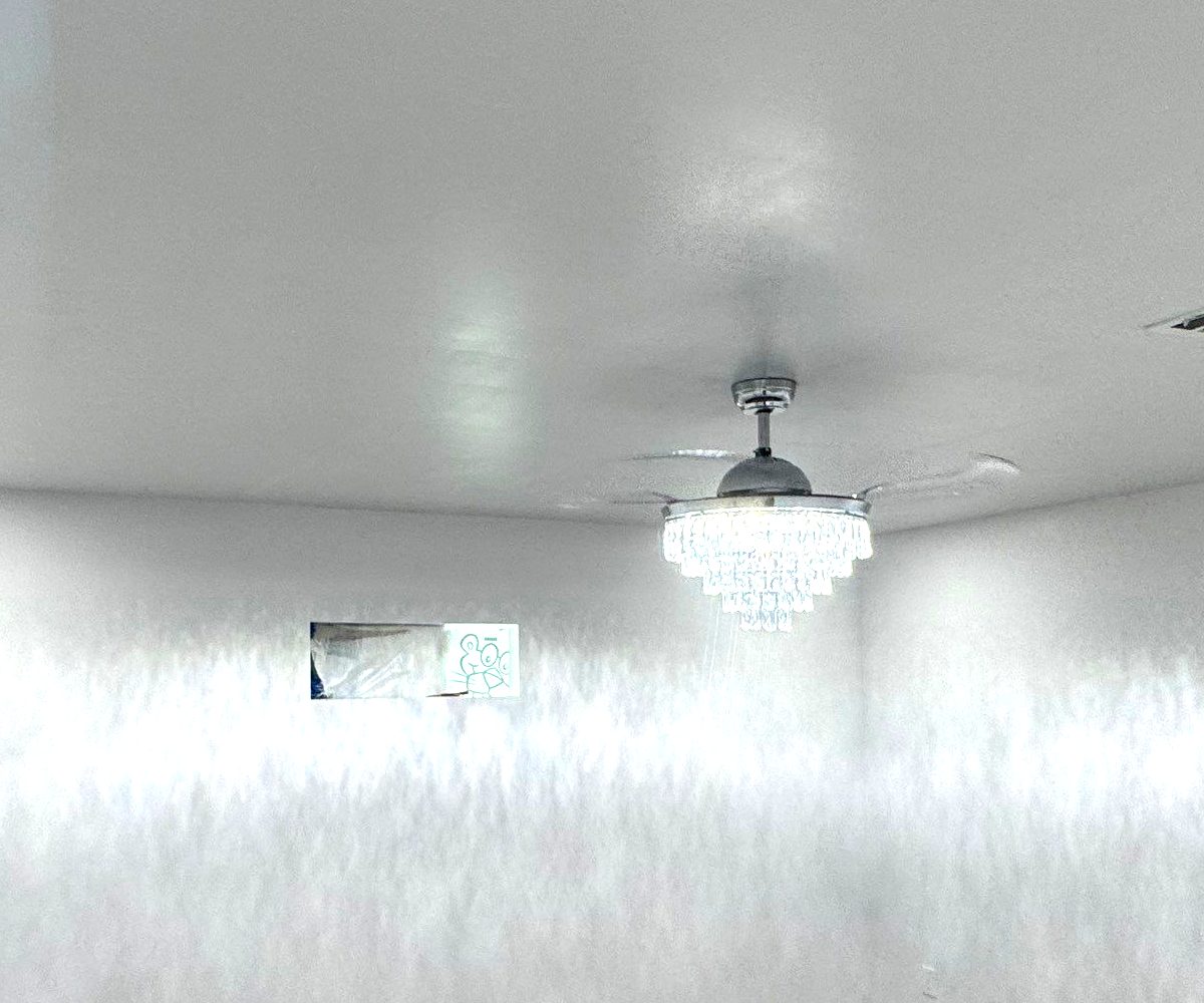 Crystal chandelier ceiling fan with retractable blades installed in a residential room.
